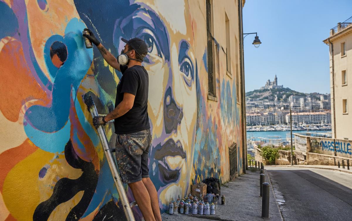 Artiste peignant une grande fresque murale colorée à Marseille